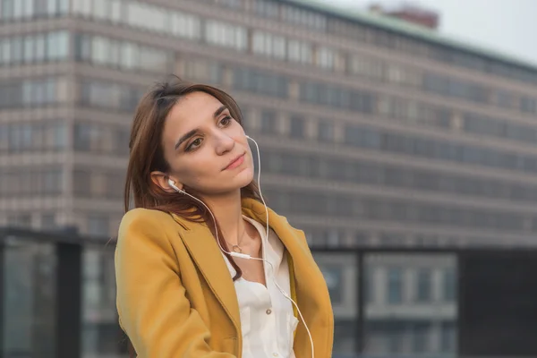 Ragazza rossa che ascolta musica per le strade della città — Foto Stock