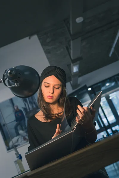 Beautiful young brunette reading book in an office — Stock Photo, Image