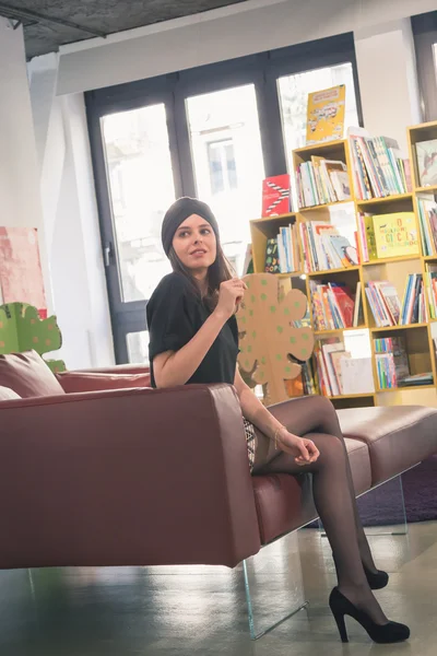 Hermosa joven morena posando en una librería — Foto de Stock