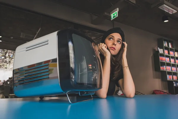 Kaunis nuori brunette poseeraa vieressä vintage tv — kuvapankkivalokuva