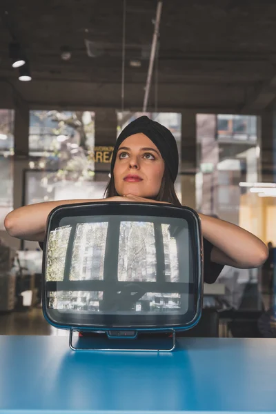 Krásná mladá brunetka pózuje vedle vinobraní tv — Stock fotografie