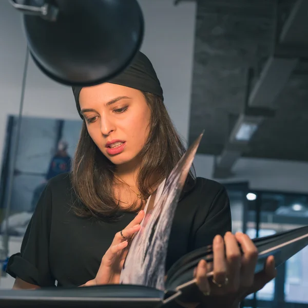 Beautiful young brunette reading book in an office — Stock Photo, Image