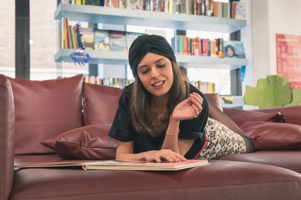 Schöne junge Brünette liest Buch in einer Buchhandlung — Stockfoto