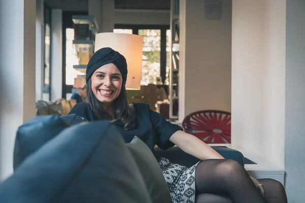 Beautiful young brunette posing on a couch — Stock Photo, Image