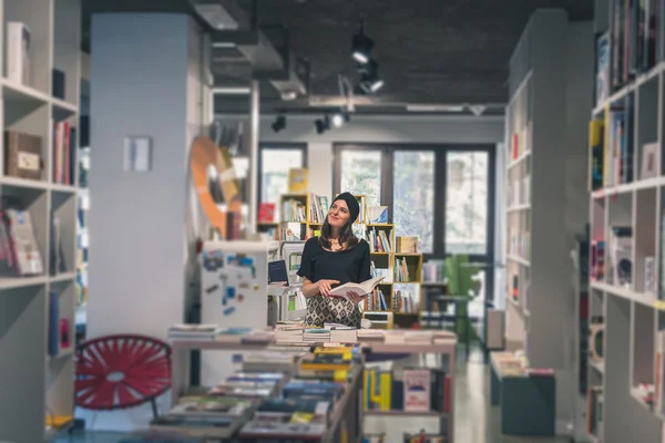 Krásná mladá brunetka pózuje v knihkupectví — Stock fotografie