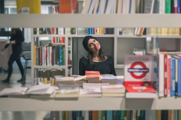 Schöne junge Brünette posiert in einer Buchhandlung — Stockfoto