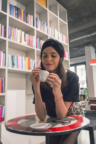 Linda jovem morena bebendo café em uma livraria — Fotografia de Stock