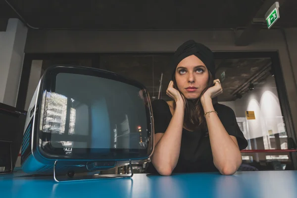 Beautiful young brunette posing beside a vintage tv — Stock Photo, Image