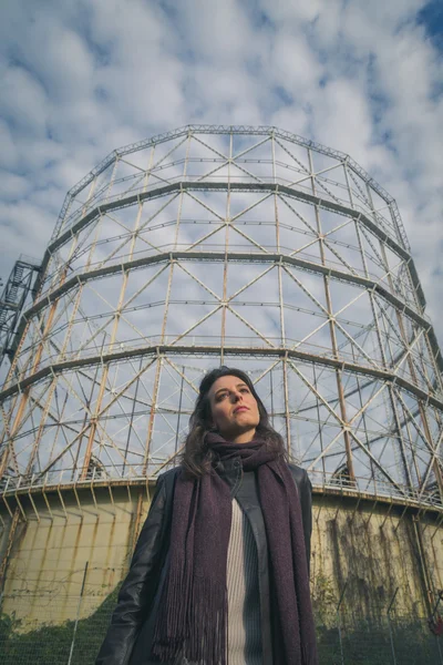 Linda jovem morena posando na frente de um gasômetro — Fotografia de Stock