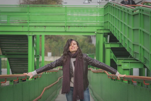 Beautiful young brunette posing on a bridge — Stock Photo, Image