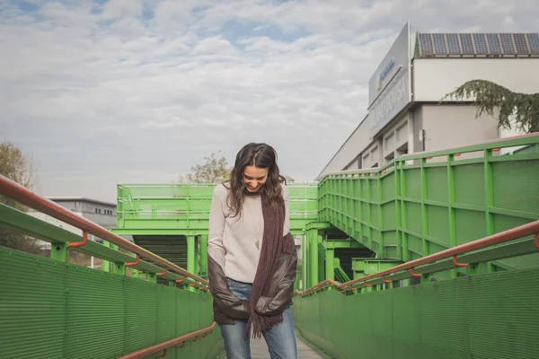 Beautiful young brunette posing on a bridge — Stock Photo, Image