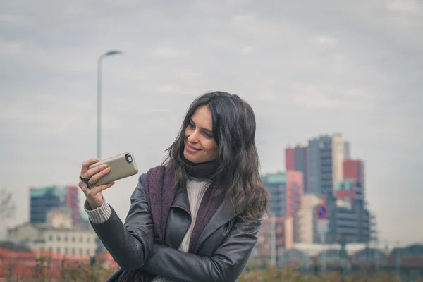 Bella giovane bruna che si fa un selfie per le strade della città — Foto Stock