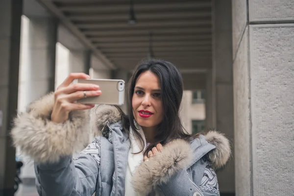 Linda jovem morena tirando uma selfie nas ruas da cidade — Fotografia de Stock