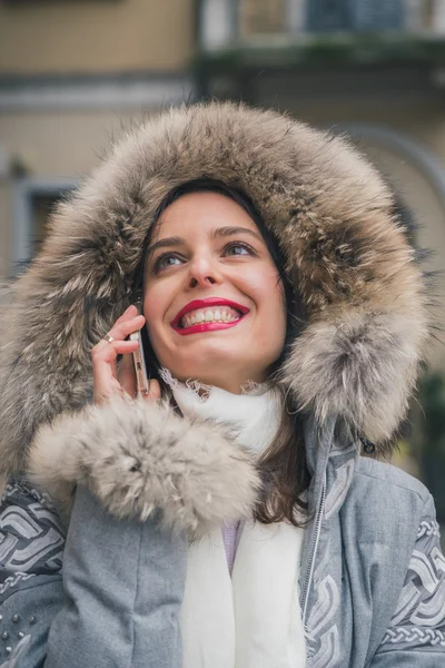 Piękna młoda brunetka rozmowy na telefon na ulicach miasta — Zdjęcie stockowe