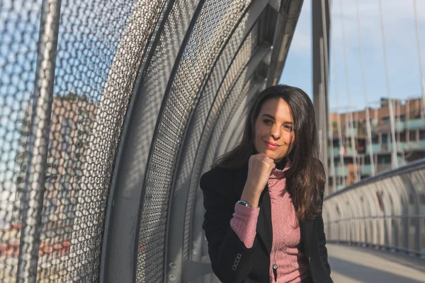 Beautiful young brunette posing on a bridge — Stock Photo, Image
