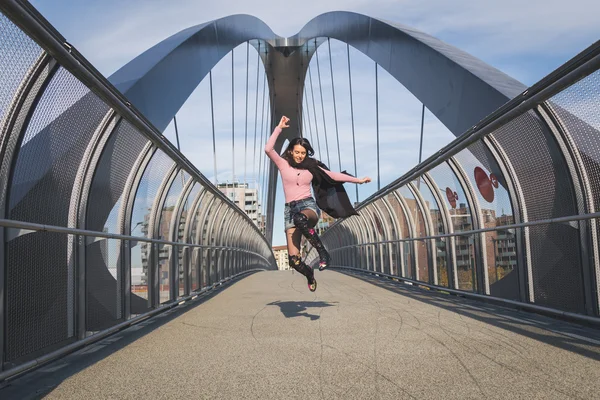 Bella giovane bruna che salta su un ponte — Foto Stock