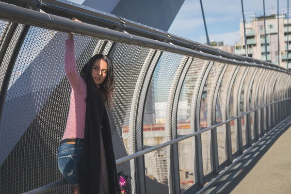 Beautiful young brunette posing on a bridge — Stock Photo, Image