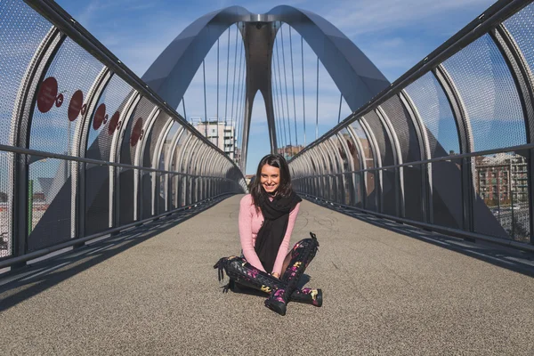 Beautiful young brunette posing on a bridge — Stock Photo, Image