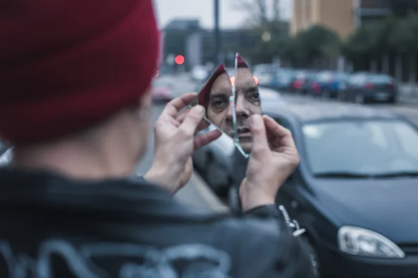 Punk guy looking at himself in a shattered mirror — Stock Photo, Image