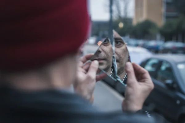 Punk guy looking at himself in a shattered mirror — Stock Photo, Image