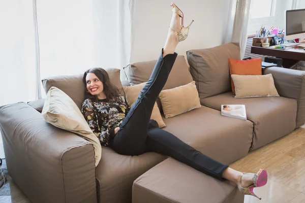 Linda jovem morena relaxante em um sofá — Fotografia de Stock