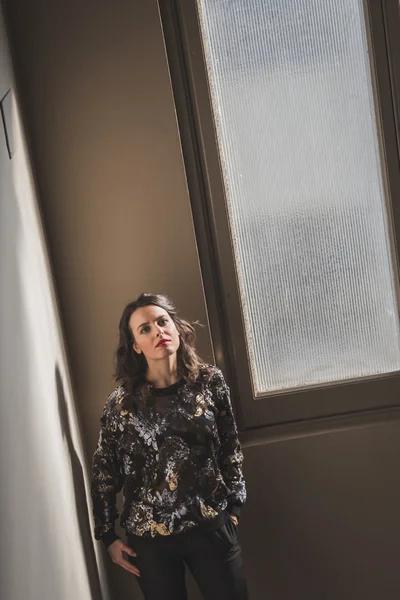 Retrato de uma bela jovem morena posando ao lado de uma janela — Fotografia de Stock