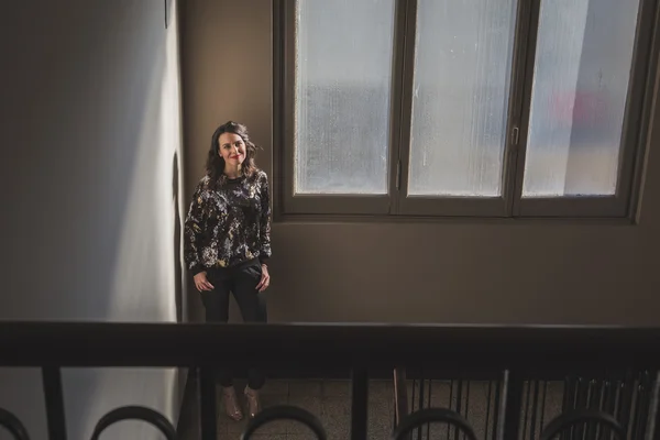 Portrett av en vakker ung brunette ved siden av et vindu – stockfoto