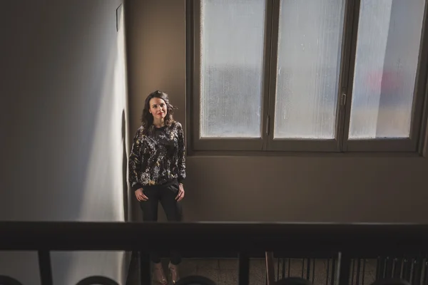 Retrato de uma bela jovem morena posando ao lado de uma janela — Fotografia de Stock