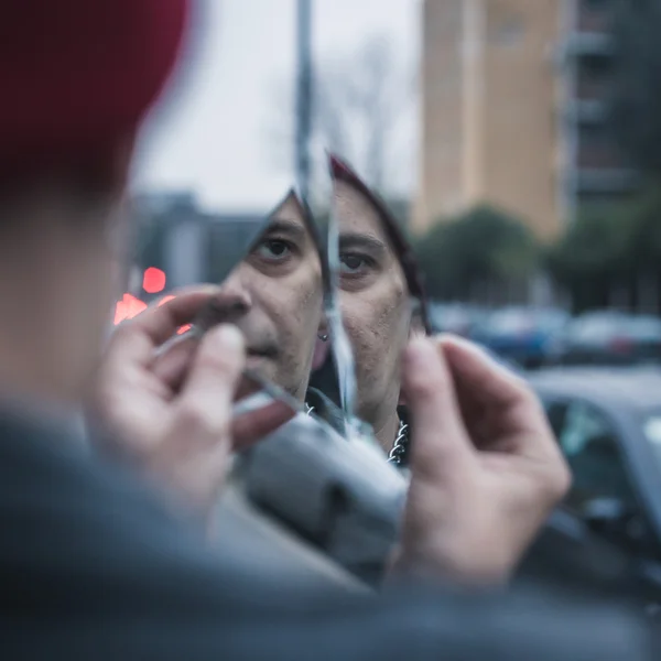 Punk cara olhando para si mesmo em um espelho quebrado — Fotografia de Stock