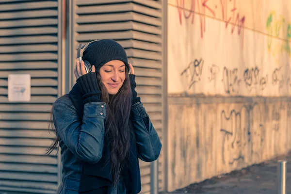 Vacker ung kvinna lyssna på musik på stadens gator — Stockfoto