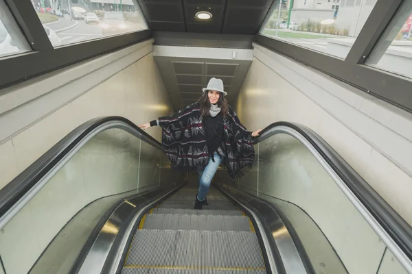 Hermosa joven morena posando en escalera mecánica — Foto de Stock