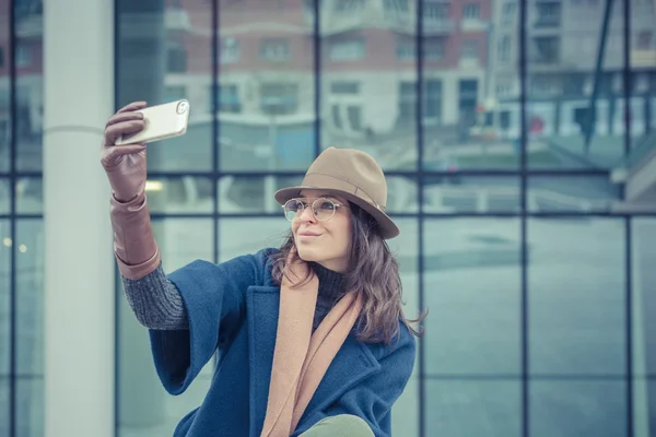 Krásná mladá brunetka s selfie v ulicích města — Stock fotografie