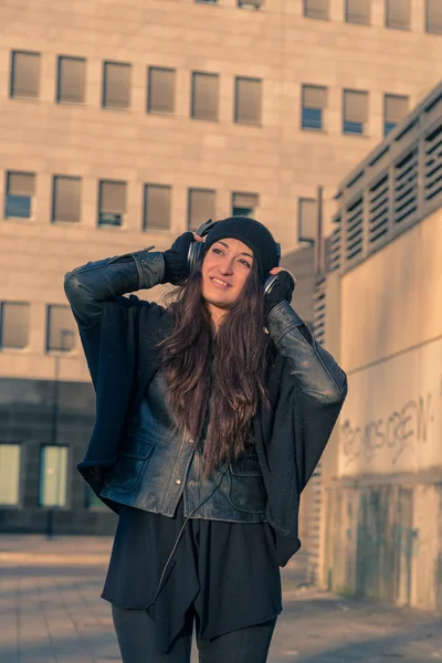 Vacker ung kvinna lyssna på musik på stadens gator — Stockfoto