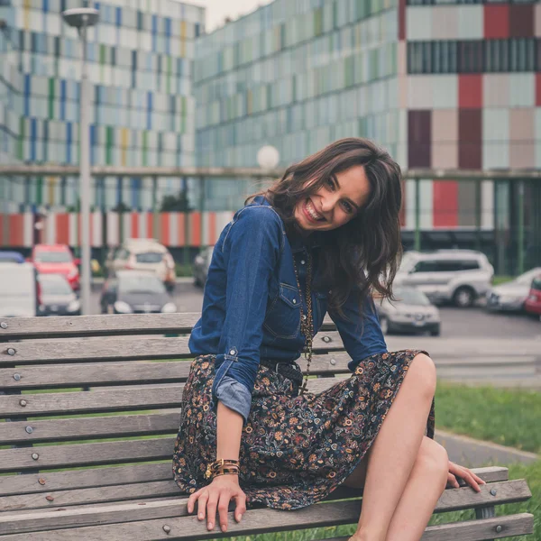 Pretty girl sitting on a bench in the street — Stock Photo, Image