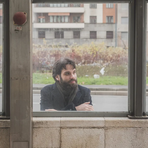 Young handsome bearded man posing behind a glass — Stock Photo, Image