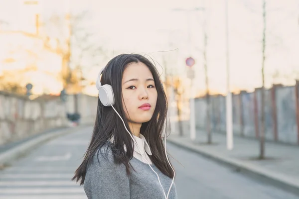 Menina chinesa bonita nova com fones de ouvido — Fotografia de Stock