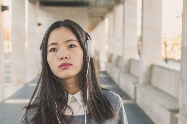 Menina chinesa bonita nova com fones de ouvido — Fotografia de Stock