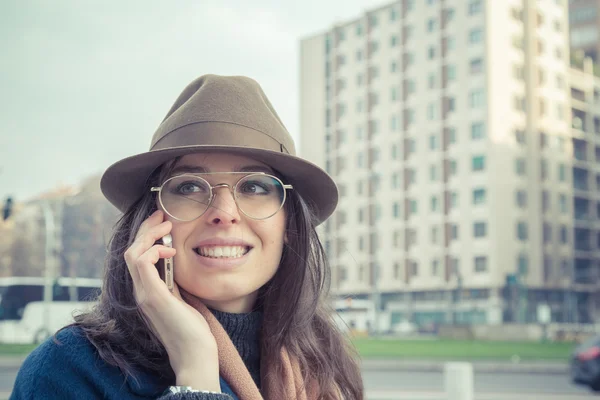 Beautiful young brunette talking on phone in the city streets — Stock Photo, Image