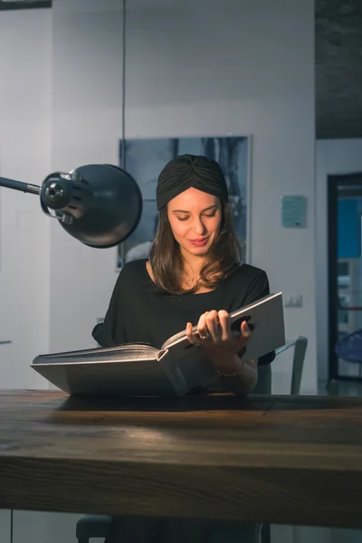 Vacker ung brunett läsa boken på ett kontor — Stockfoto