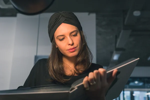 Schöne junge Brünette liest Buch in einem Büro — Stockfoto