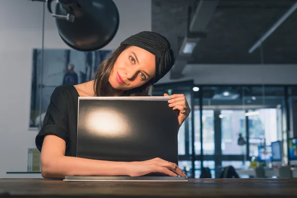 Beautiful young brunette reading book in an office — Stock Photo, Image