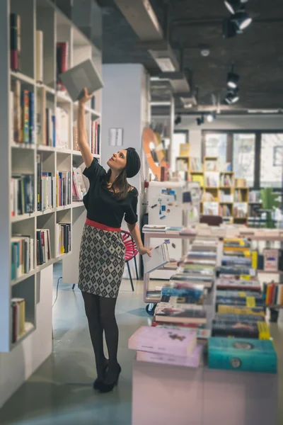 Schöne junge Brünette posiert in einer Buchhandlung — Stockfoto