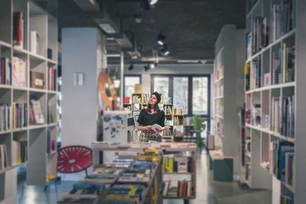 Beautiful young brunette posing in a bookstore — Stock Photo, Image