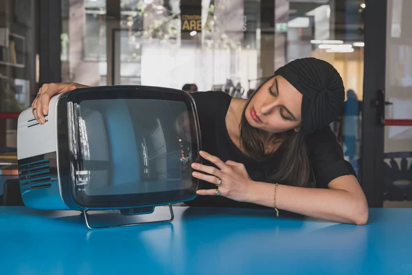 Beautiful young brunette posing beside a vintage tv — Stock Photo, Image