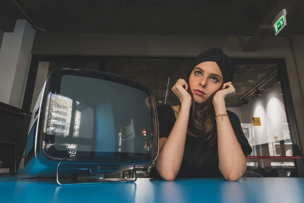 Belle jeune brune posant à côté d'une télévision vintage — Photo