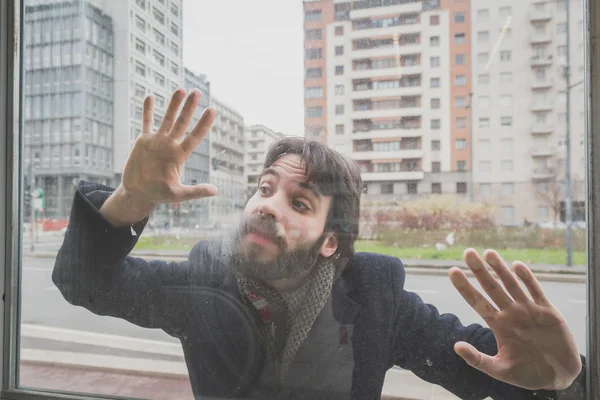 Homem barbudo bonito jovem posando atrás de um copo — Fotografia de Stock