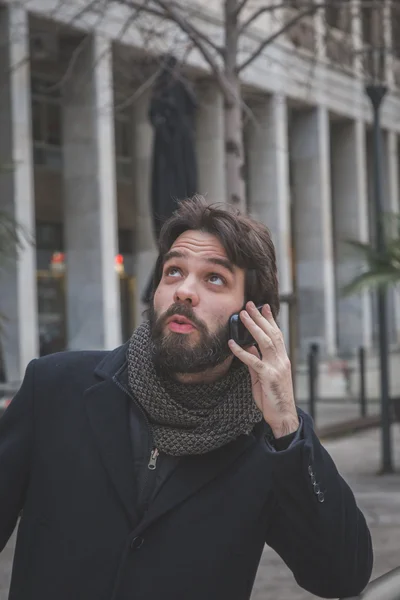 Молодой красивый бородатый мужчина разговаривает по телефону — стоковое фото
