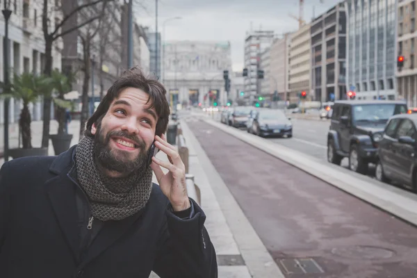 Fiatal jóképű szakállas ember beszél telefonon — Stock Fotó
