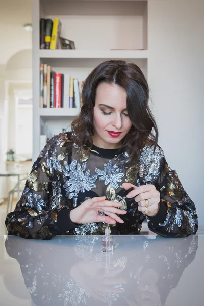 Beautiful young brunette putting on nail polish — Stock Photo, Image