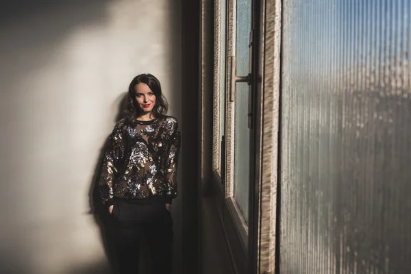 Portrett av en vakker ung brunette ved siden av et vindu – stockfoto